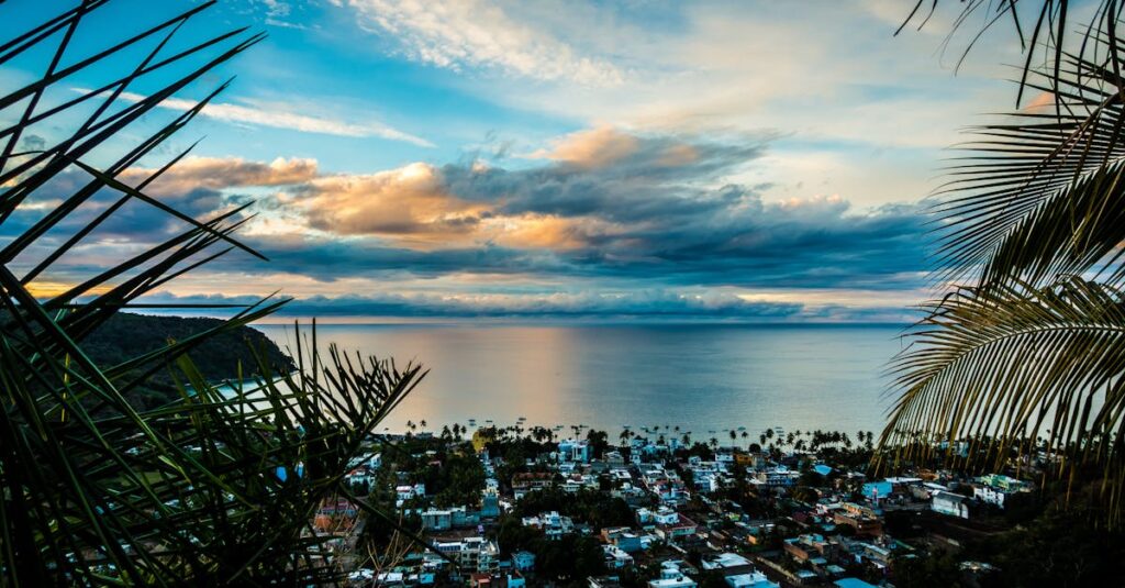 Breathtaking view of a coastal town, ocean and palm trees at sunset.