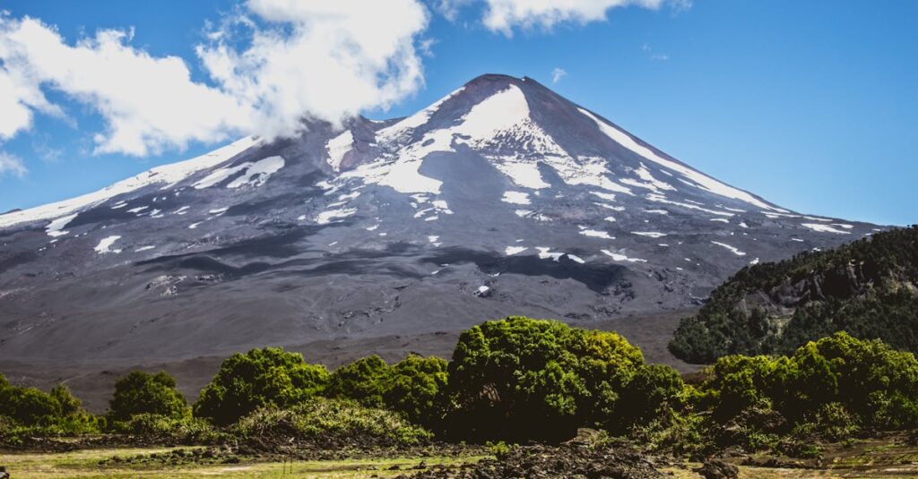 Stunning view of Llaima Volcano with vibrant greenery under a clear blue sky in Araucanía, Chile.